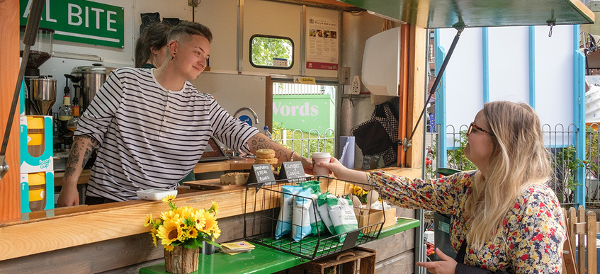 Bright coffee cart, staff member serves smiling customer